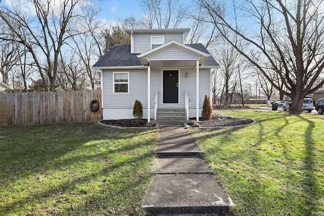 view of front of property featuring roof with shingles, fence, and a front lawn