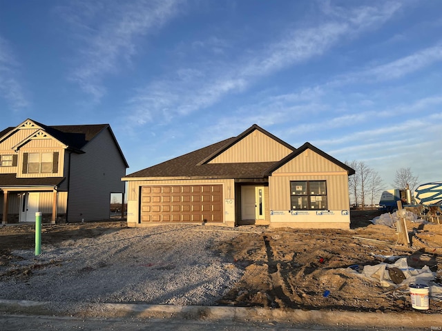 view of front of house featuring a garage, gravel driveway, and a shingled roof