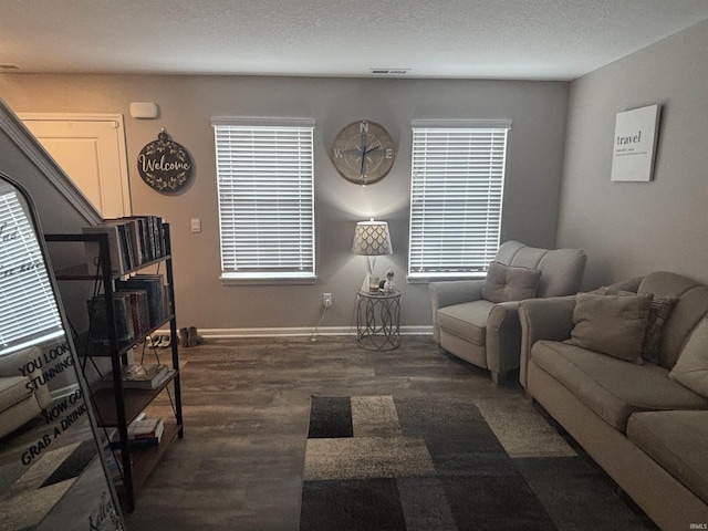 living room featuring visible vents, a textured ceiling, baseboards, and wood finished floors