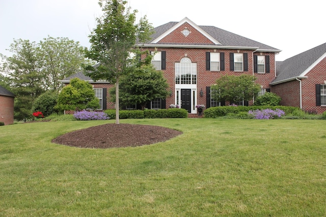 colonial home featuring a front yard and brick siding