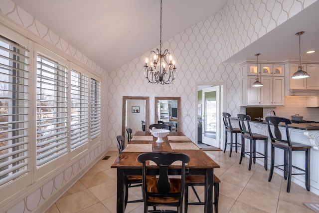 dining space with wallpapered walls, vaulted ceiling, an inviting chandelier, and light tile patterned flooring