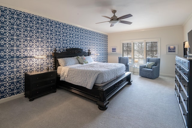 carpeted bedroom featuring ceiling fan, an accent wall, baseboards, and crown molding