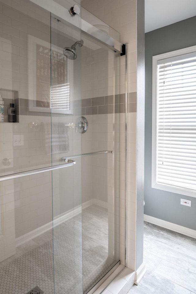 full bath with plenty of natural light, a shower stall, and baseboards