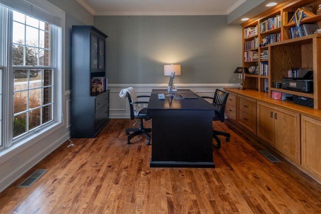 office space featuring a wainscoted wall, dark wood-style floors, visible vents, and ornamental molding