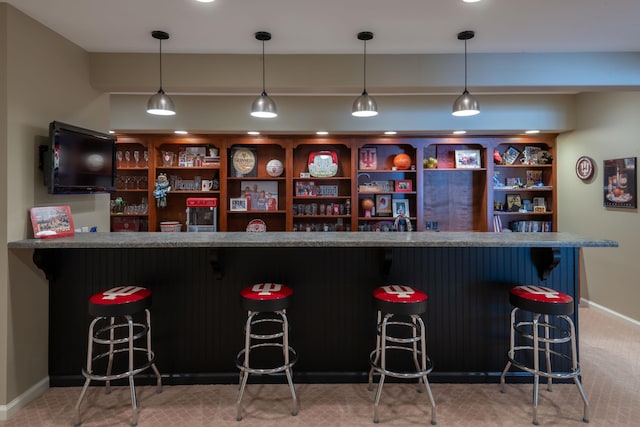 bar featuring carpet, baseboards, indoor wet bar, and decorative light fixtures