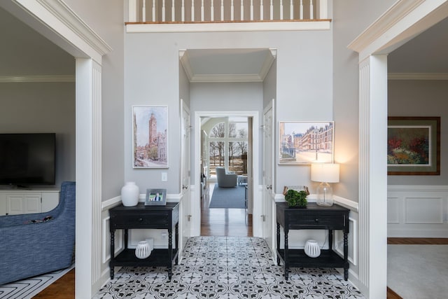 hall featuring a wainscoted wall, a decorative wall, and crown molding