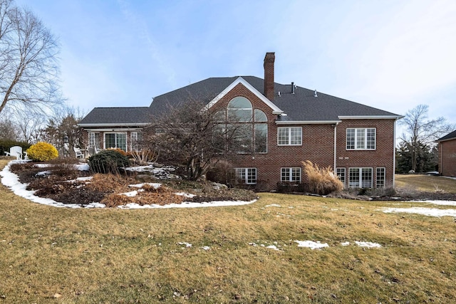 back of house featuring brick siding, a lawn, and a chimney