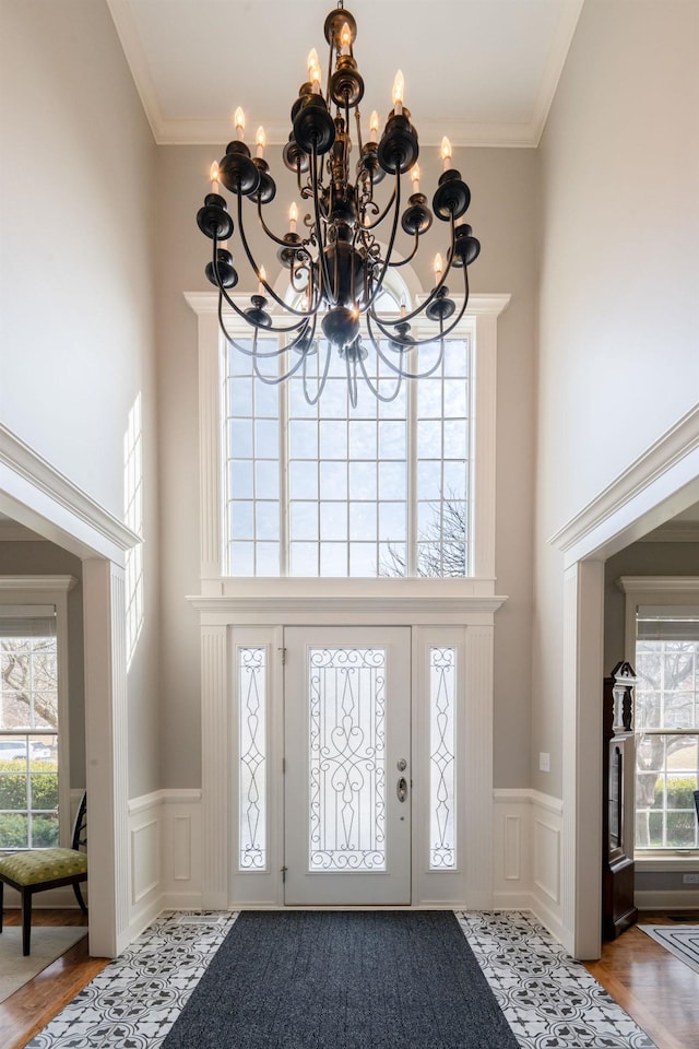 entryway with ornamental molding, wainscoting, and a high ceiling