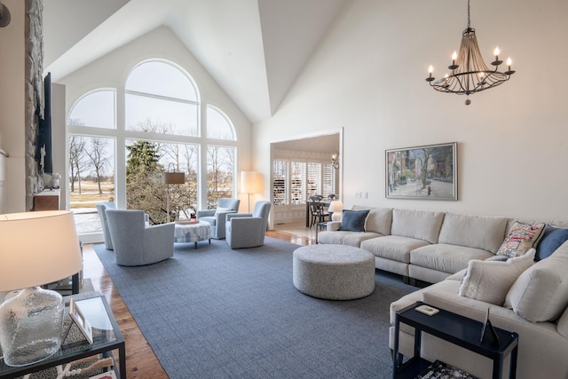 living area featuring high vaulted ceiling, a chandelier, and wood finished floors