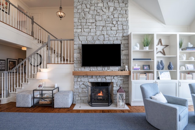 living area featuring crown molding, a fireplace, stairway, wood finished floors, and high vaulted ceiling