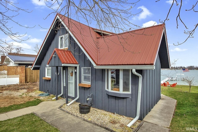 view of front of home with board and batten siding, metal roof, an outdoor structure, and fence