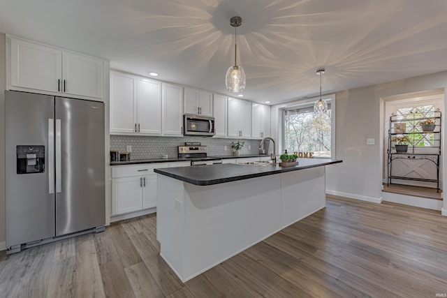 kitchen with tasteful backsplash, white cabinets, dark countertops, light wood-style flooring, and stainless steel appliances