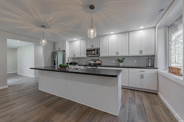 kitchen with appliances with stainless steel finishes, dark countertops, white cabinetry, and tasteful backsplash