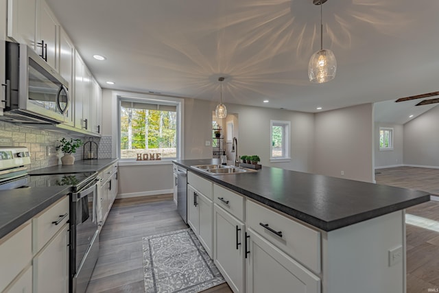 kitchen with dark countertops, backsplash, stainless steel appliances, and a sink