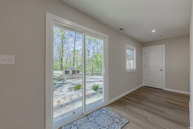 doorway featuring light wood finished floors, visible vents, baseboards, and recessed lighting