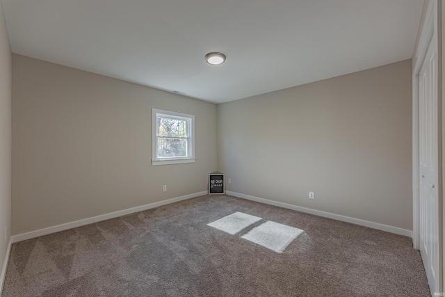 carpeted spare room featuring baseboards