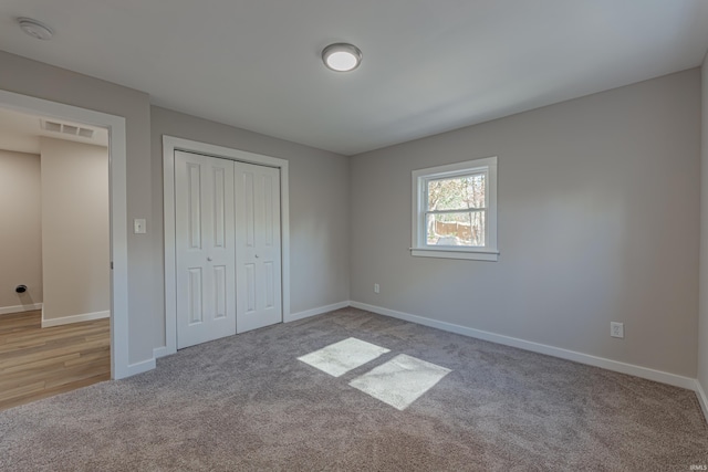 unfurnished bedroom with light carpet, baseboards, visible vents, and a closet