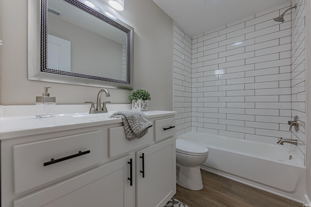 full bath with bathtub / shower combination, toilet, wood finished floors, visible vents, and vanity