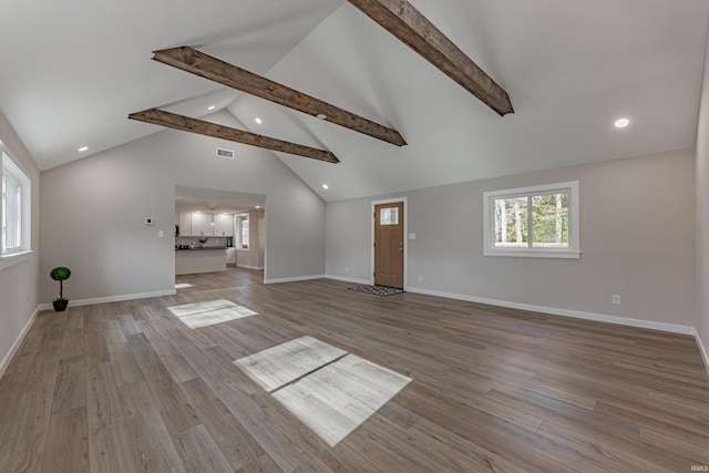 unfurnished living room featuring high vaulted ceiling, baseboards, beam ceiling, and wood finished floors