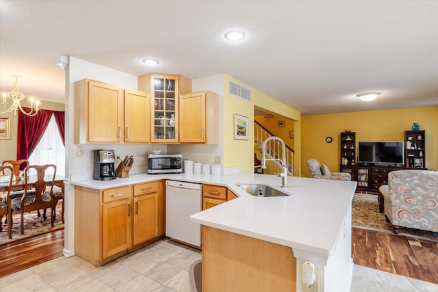 kitchen with stainless steel microwave, visible vents, white dishwasher, a sink, and a peninsula