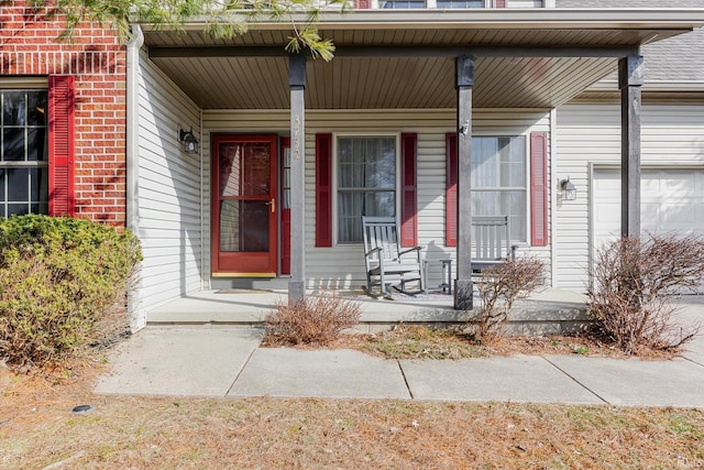 doorway to property with covered porch, brick siding, and an attached garage