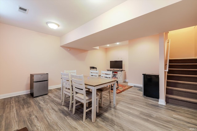 dining room featuring stairs, wood finished floors, visible vents, and baseboards