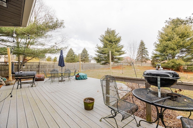 deck featuring outdoor dining space, a fenced backyard, and a lawn