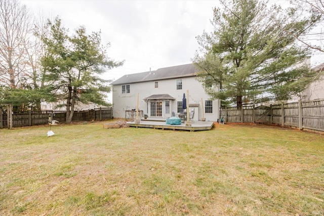 back of property with a fenced backyard, a deck, and a yard