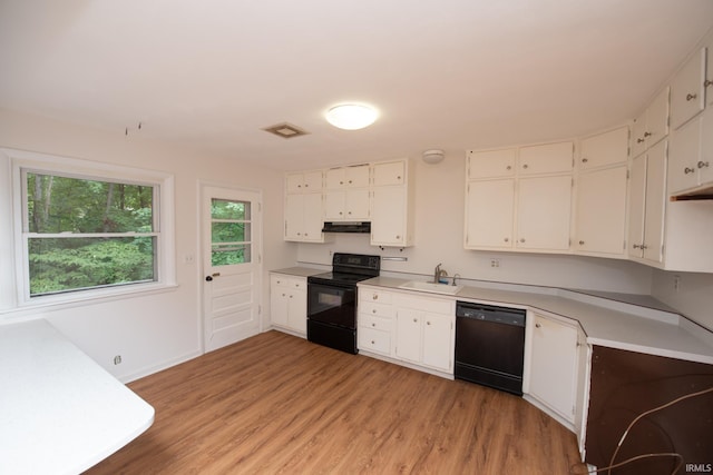 kitchen with visible vents, light wood-style floors, under cabinet range hood, black appliances, and a sink