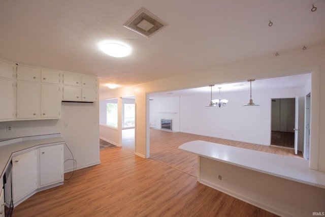 kitchen with visible vents, white cabinets, a glass covered fireplace, light wood-style flooring, and light countertops