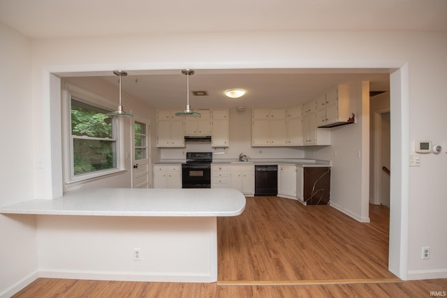 kitchen with light countertops, under cabinet range hood, black appliances, and a peninsula