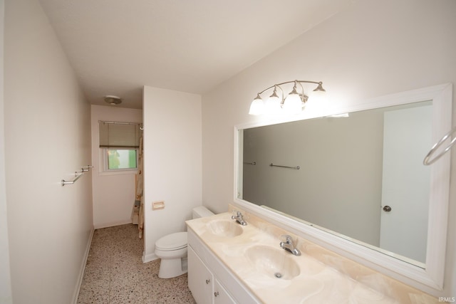 full bath with double vanity, a sink, toilet, and speckled floor