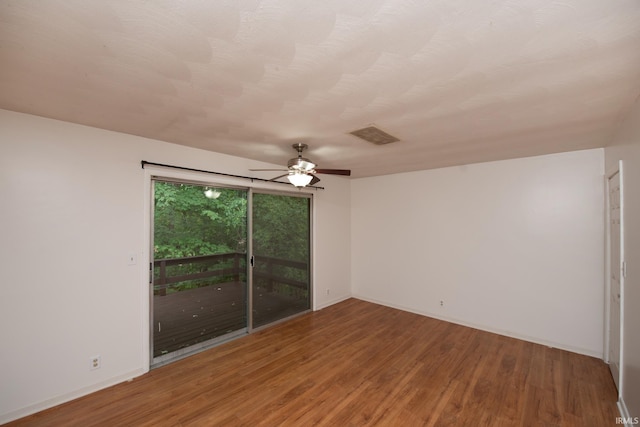 spare room with a ceiling fan, wood finished floors, visible vents, and baseboards