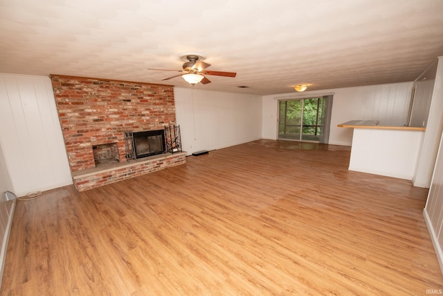 unfurnished living room with light wood-style floors, ceiling fan, and a fireplace