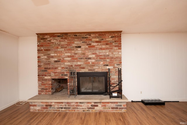 details with a brick fireplace and wood finished floors