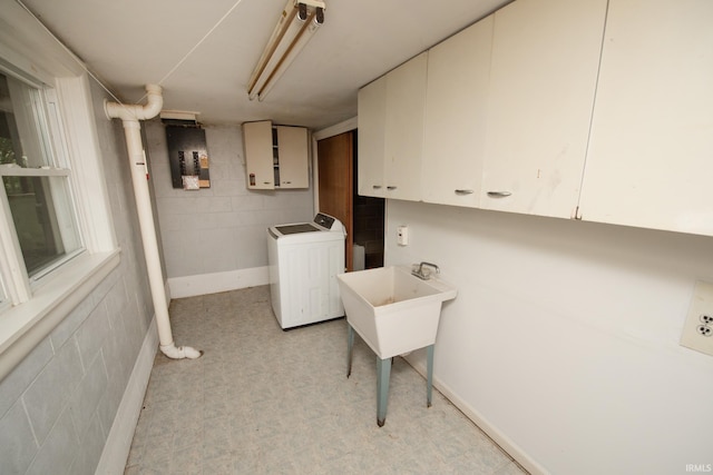 washroom with concrete block wall, cabinet space, and washer / clothes dryer