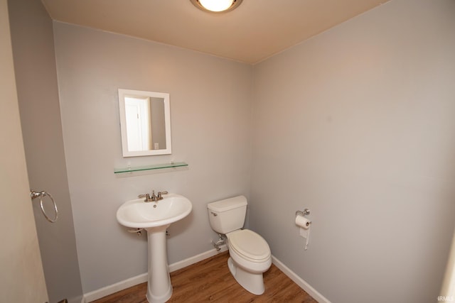 half bath with wood finished floors, toilet, and baseboards