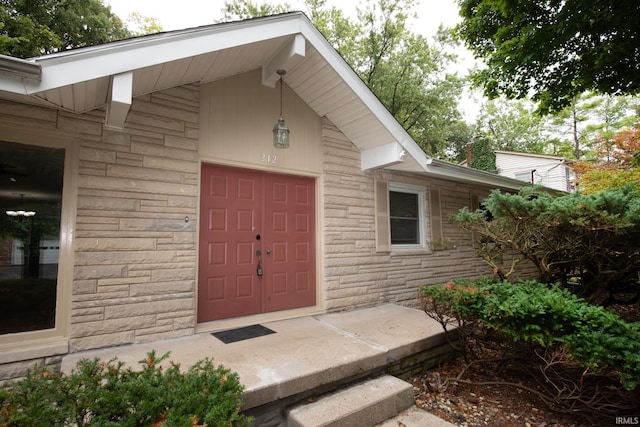 view of exterior entry with an attached garage and stone siding