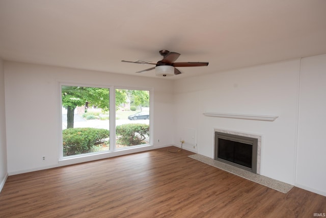 unfurnished living room with a fireplace with flush hearth, wood finished floors, a ceiling fan, and baseboards