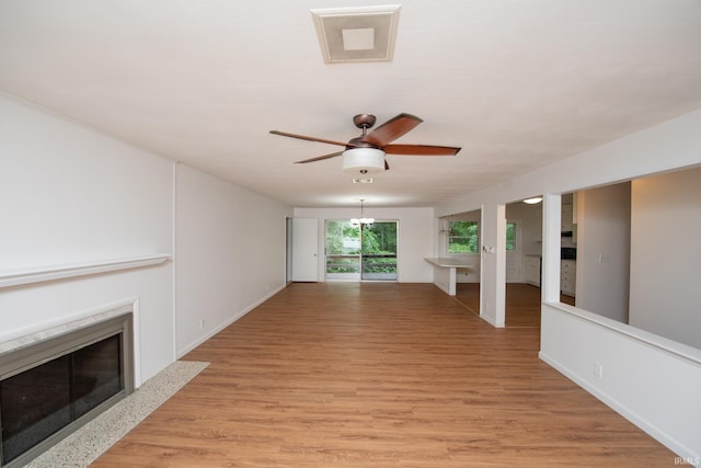 unfurnished living room with ceiling fan, a fireplace, visible vents, baseboards, and light wood-type flooring