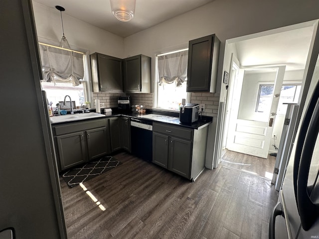 kitchen featuring dark wood-style flooring, a sink, backsplash, dishwasher, and dark countertops