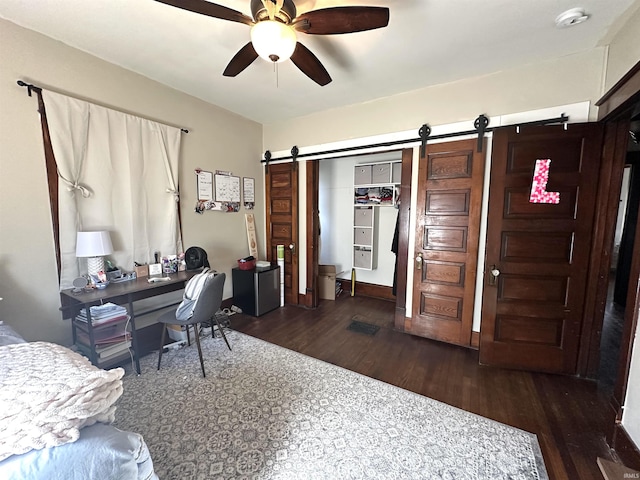 office space with wood finished floors, ceiling fan, and a barn door