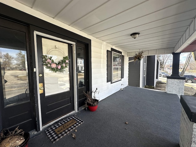 doorway to property with a porch and concrete block siding