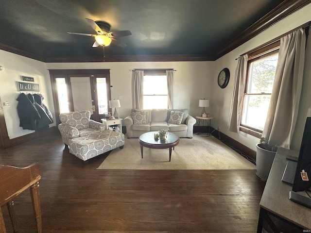 living area with baseboards, ceiling fan, wood finished floors, and crown molding