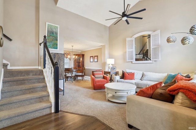 living room with stairs, ceiling fan with notable chandelier, and wood finished floors