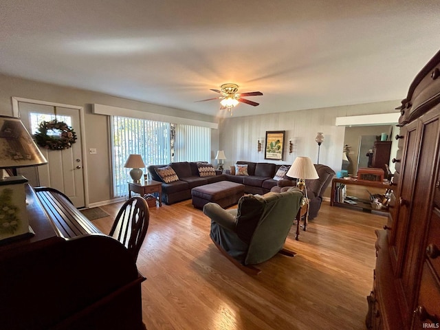 living room with ceiling fan, baseboards, and wood finished floors