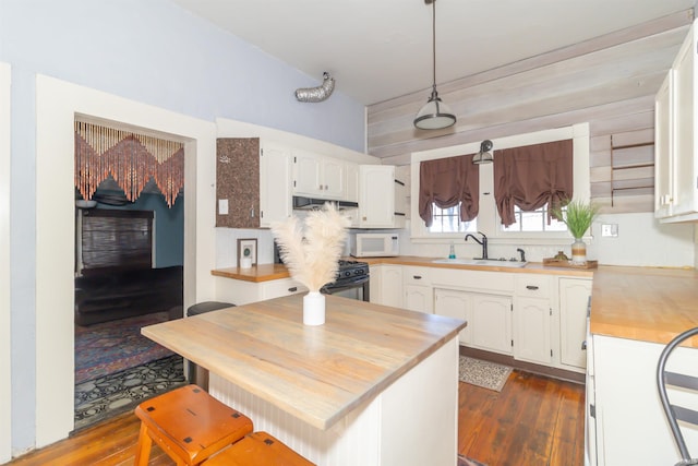 kitchen with white microwave, a sink, wood counters, and white cabinets