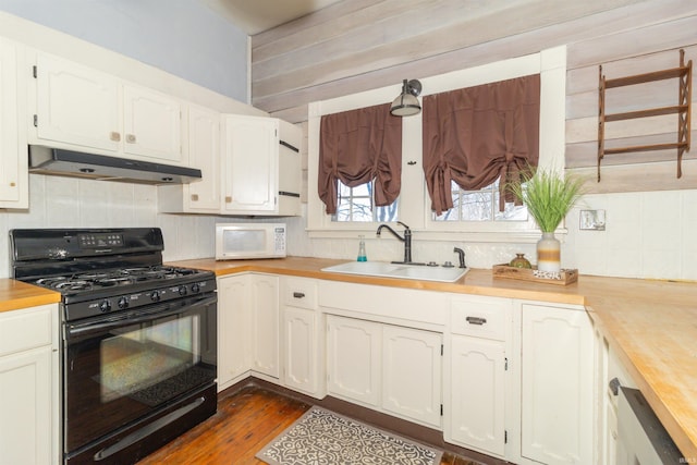 kitchen with wooden counters, black gas range oven, white microwave, a sink, and under cabinet range hood