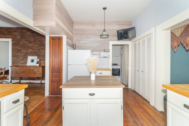 kitchen with butcher block countertops, freestanding refrigerator, washer / clothes dryer, and white cabinetry