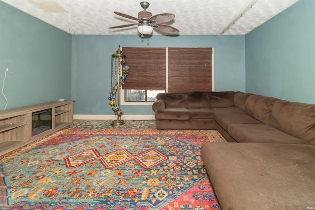 living area featuring a ceiling fan, a textured ceiling, and baseboards